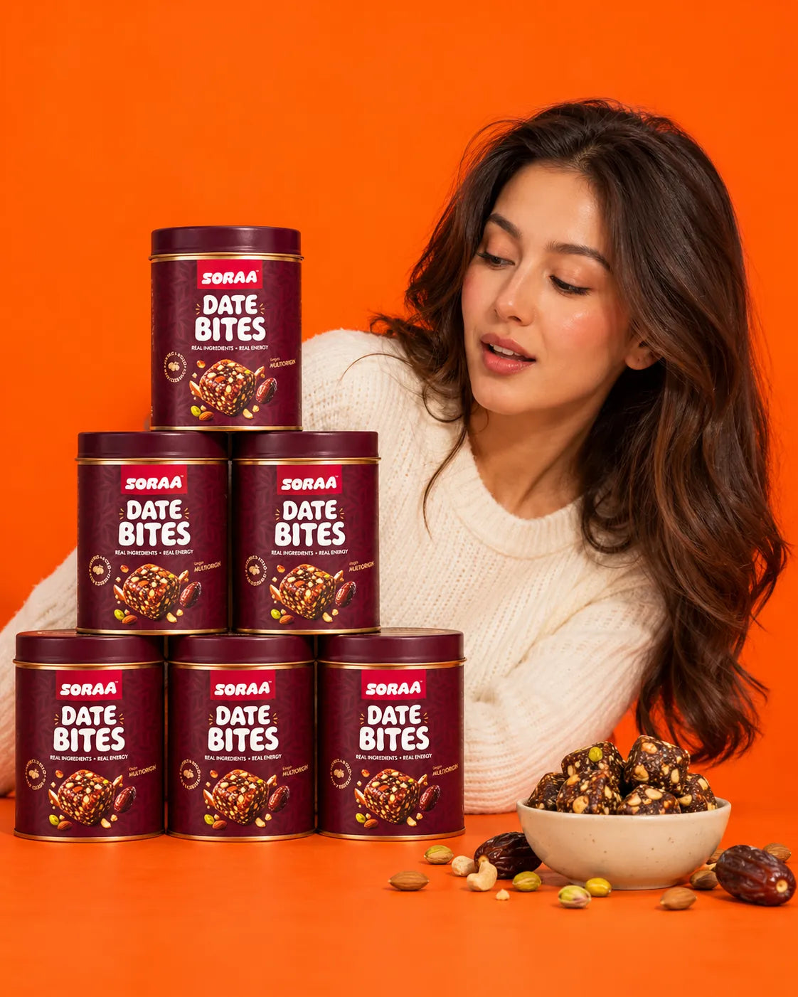 SORAA Date Bites tins stacked beside a smiling woman